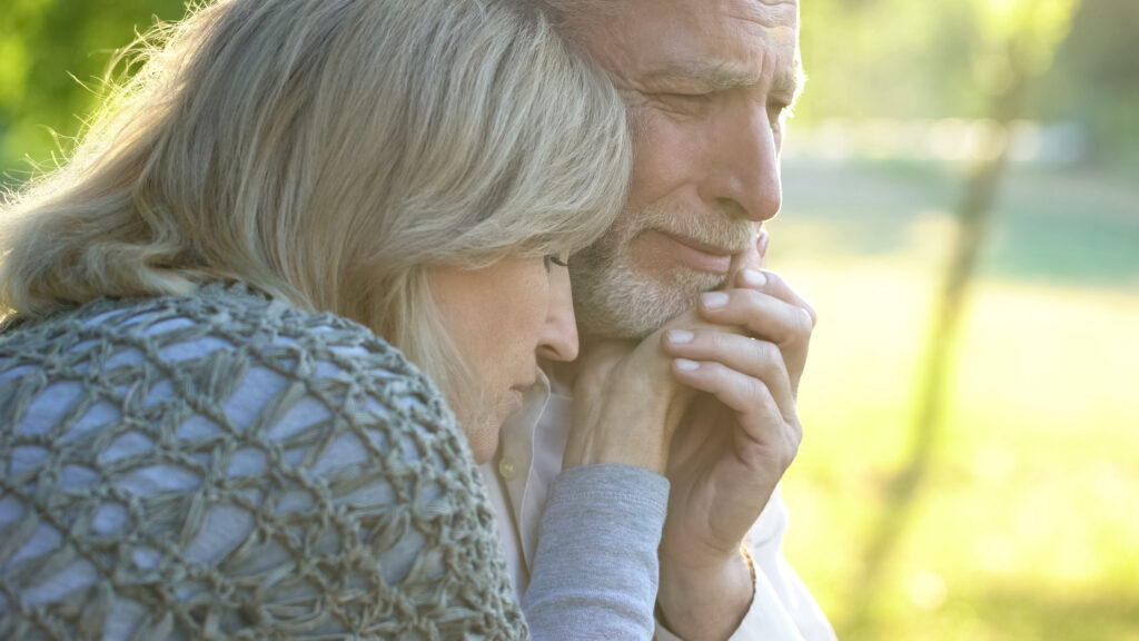 Old woman supporting and hugging her crying husband