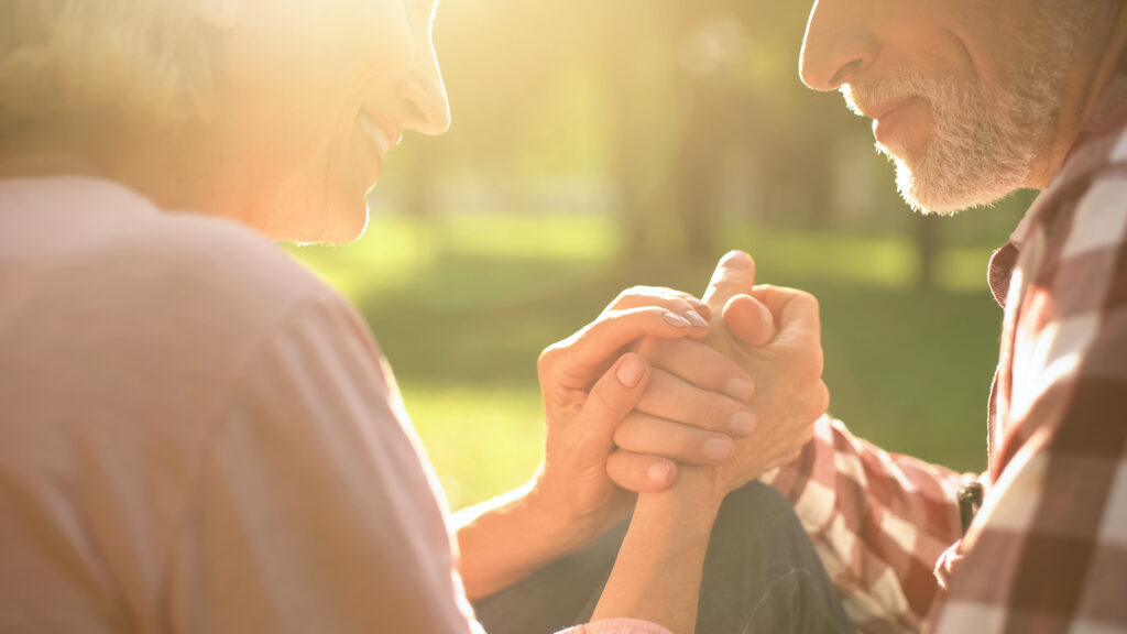 Smiling retired couple relaxing in park, holding hands