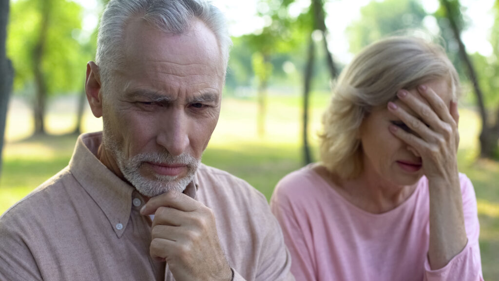 Senior man looking away while wife cries next to him