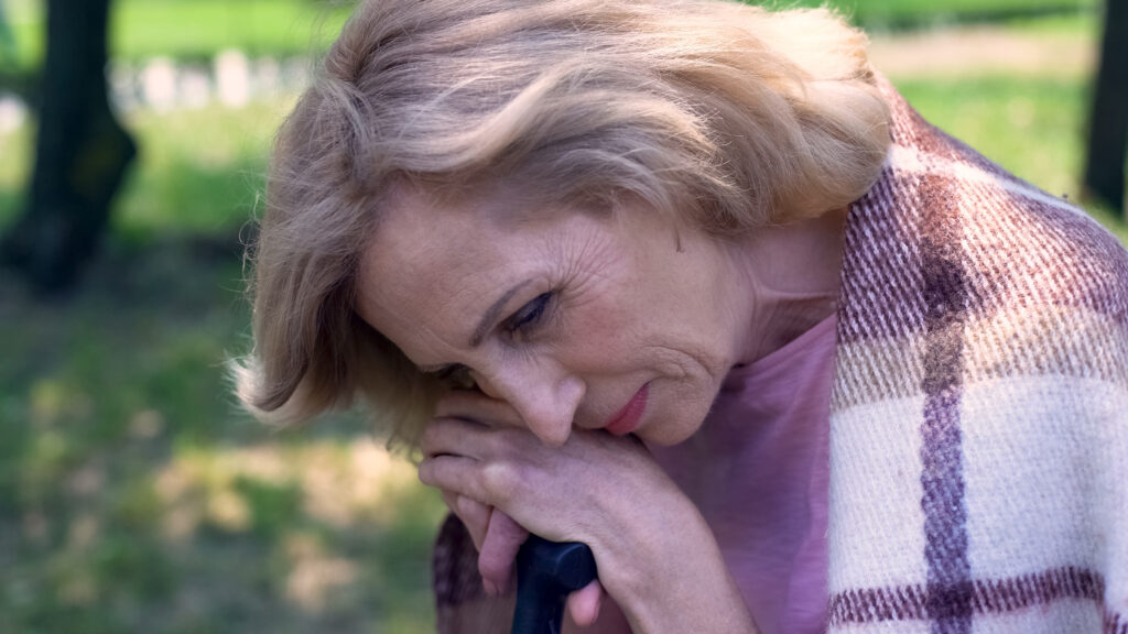 Sad grandmother sitting outside worried  